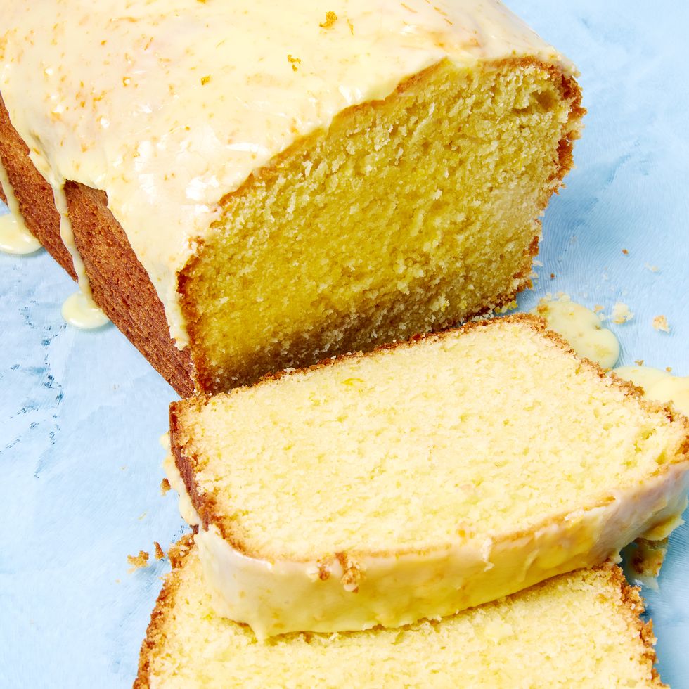 orange loaf cake glazed in orange icing with a few slices cut out of it