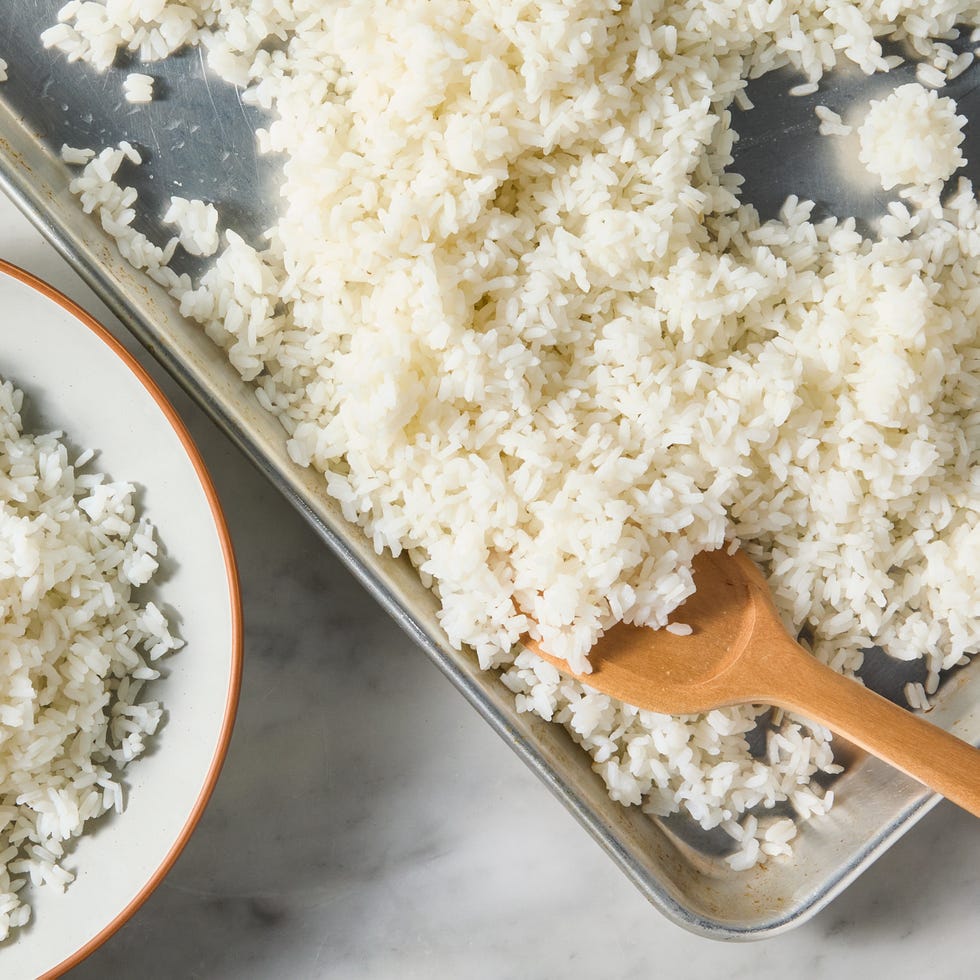sushi rice on a sheet tray with a wooden spoon next to a bowl