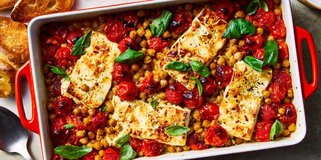 baked feta chickpeas in a casserole dish with roasted tomatoes and basil