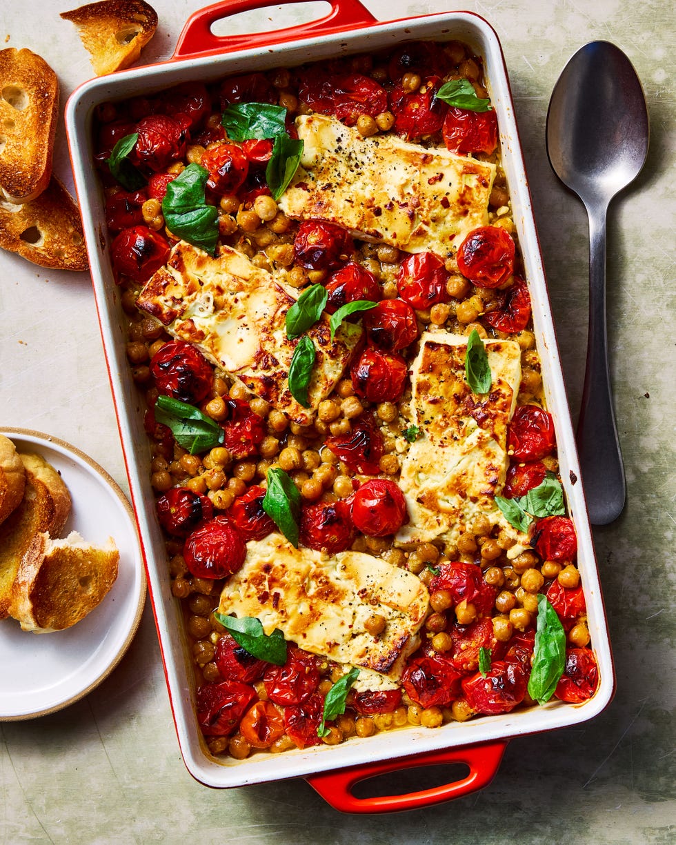 baked feta chickpeas in a casserole dish surrounded by crostini