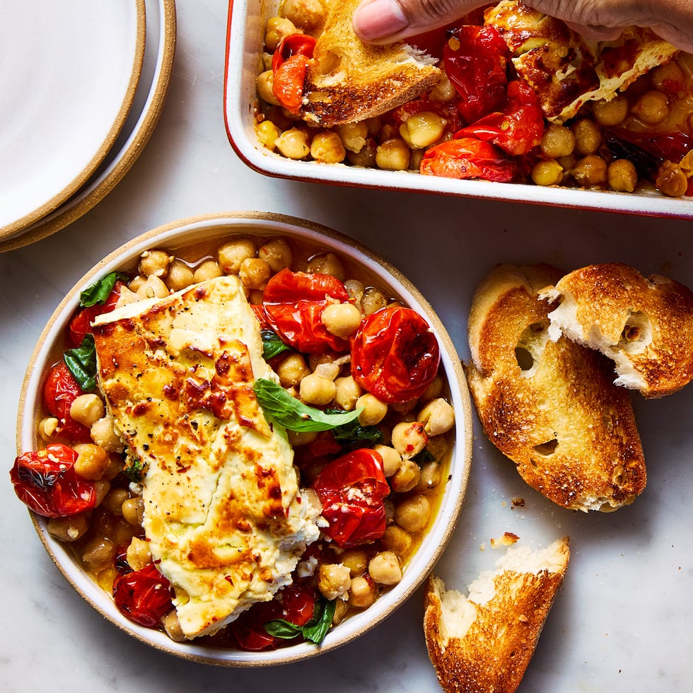 baked feta chickpeas in a bowl topped with basil beside crostini