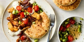 strips of chicken thigh are marinated in greek yogurt, cumin, coriander, and paprika, roasted on a sheet pan with red onion, then topped with a bright cucumber tomato salad and herby tahini yogurt dressing