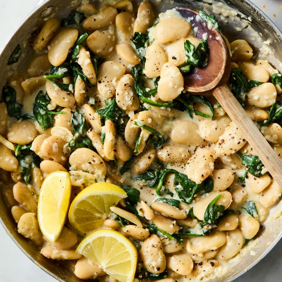 creamy lemon garlic butter beans in a pan with a wooden spoon