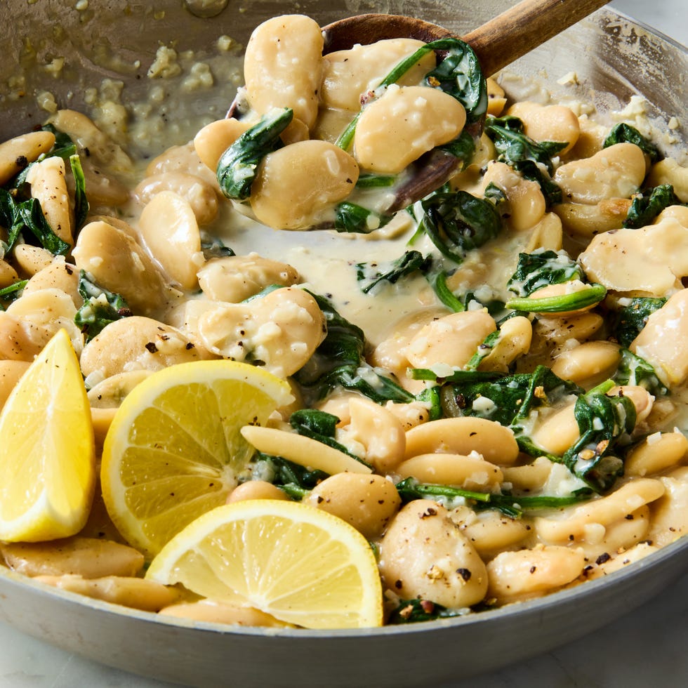 a spoonful of creamy lemon garlic butter beans being lifted up from the pan