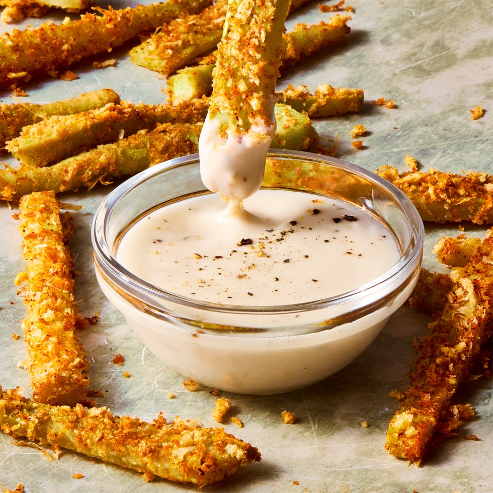 crispy parmesan broccoli stem fry being dipped into a bowl of ranch