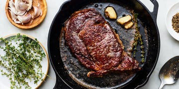 reverse sear steak in a pan with thyme sprigs and garlic cloves
