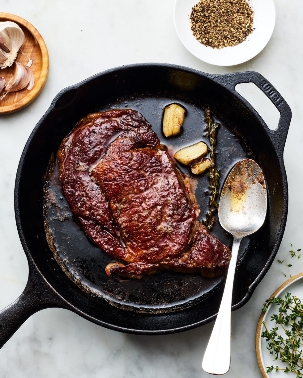 reverse sear steak in a cast iron pan with a spoon