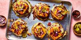 roasted cabbage burgers on a sheet tray topped with american cheese, bacon, red on ion, pickles, ketchup, and mustard