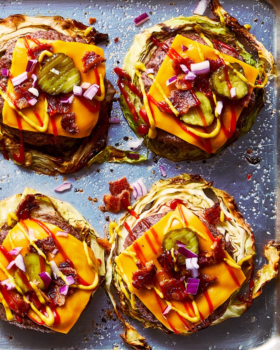 roasted cabbage burgers on a sheet pan topped with american cheese, bacon, red onion, pickles, ketchup, and mustard