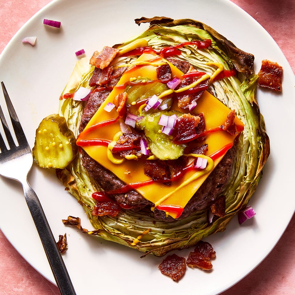 roasted cabbage burger topped with american cheese, bacon, red pepper, pickles, ketchup, and mustard on a plate