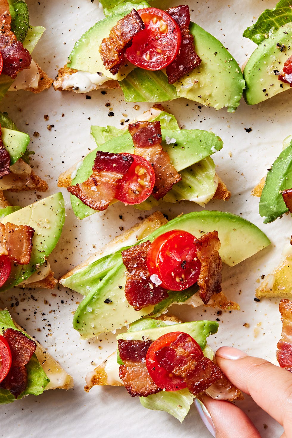 white toast points topped with lettuce, avocado, lettuce, and tomato