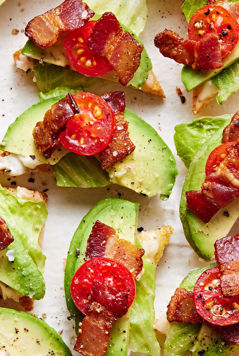 white toast points topped with lettuce, avocado, lettuce, and tomato