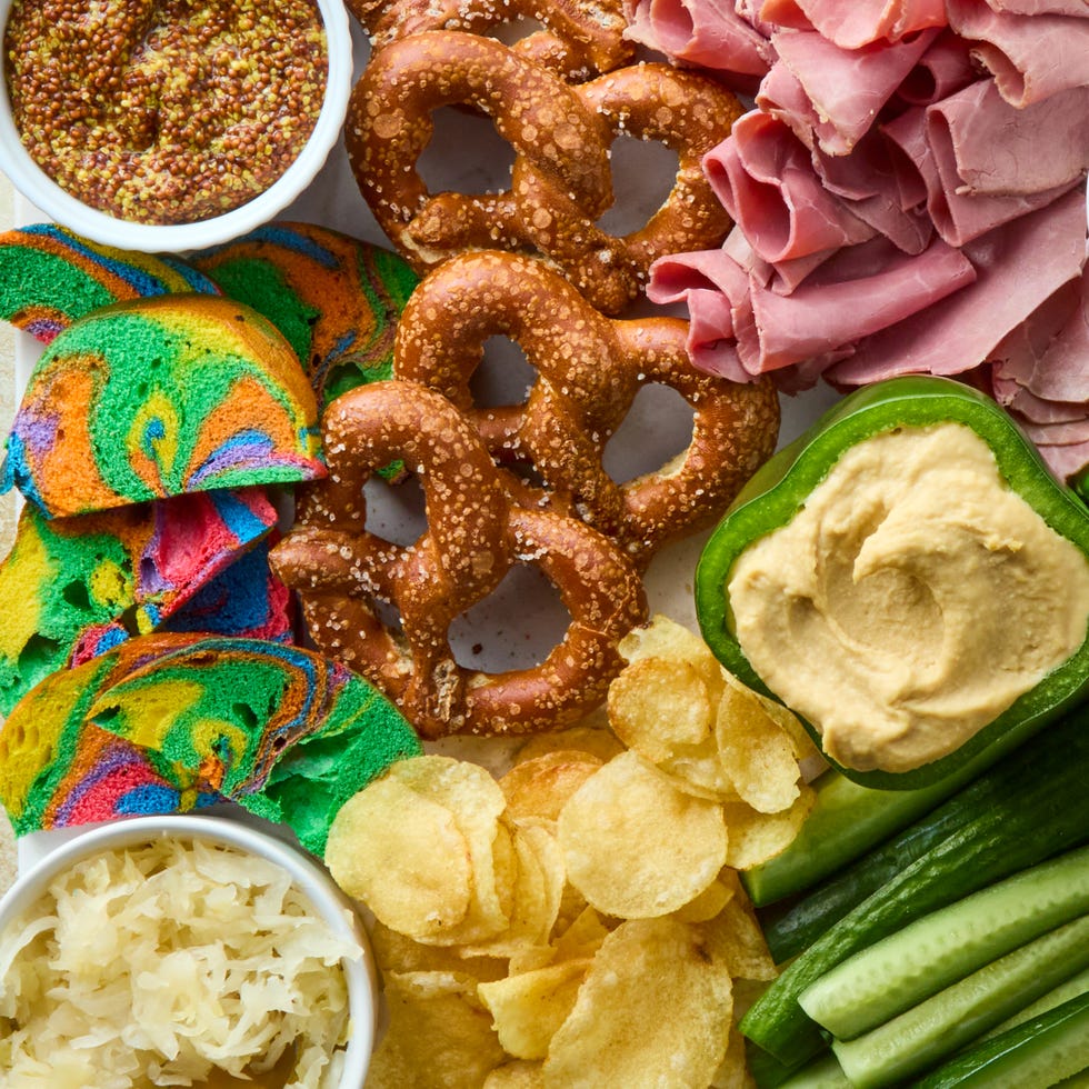 decked out board is loaded with corned beef, irish cheddar, kettle cooked potato chips, hard pretzels, rainbow bagel chips, and fresh veggies then surrounded by baby gherkin pickles, grainy mustard, sauerkraut, and dip stuffed bell peppers