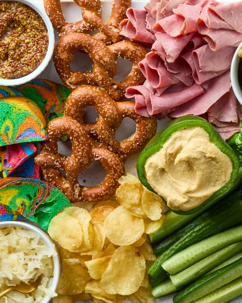 decked out board is loaded with corned beef, irish cheddar, kettle cooked potato chips, hard pretzels, rainbow bagel chips, and fresh veggies then surrounded by baby gherkin pickles, grainy mustard, sauerkraut, and dip stuffed bell peppers