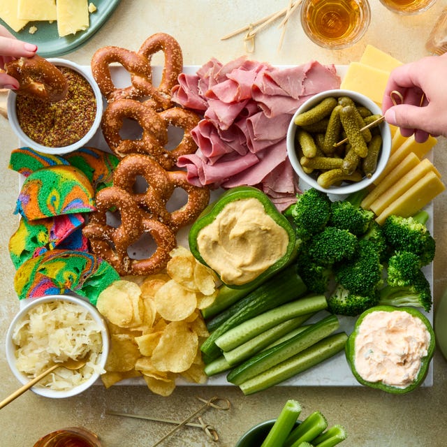 Shamrockuterie Board decked out board is loaded with corned beef, irish cheddar, kettle cooked potato chips, hard pretzels, rainbow bagel chips, and fresh veggies then surrounded by baby gherkin pickles, grainy mustard, sauerkraut, and dip stuffed bell peppers