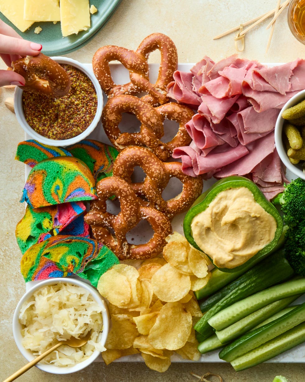 decked out board is loaded with corned beef, irish cheddar, kettle cooked potato chips, hard pretzels, rainbow bagel chips, and fresh veggies then surrounded by baby gherkin pickles, grainy mustard, sauerkraut, and dip stuffed bell peppers