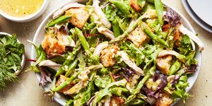 spring chicken panzanella salad topped with asparagus, peas, and shredded chicken
