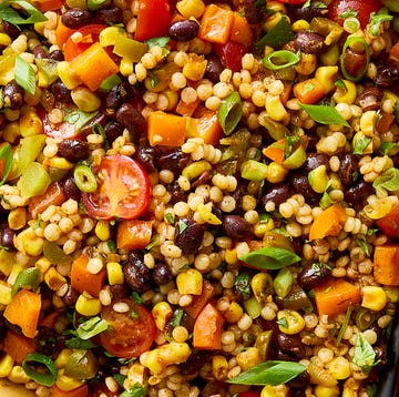 a bowl with pearl couscous, black beans, corn, bell peppers, cherry tomatoes, scallions, cilantro, and pickled jalapenos