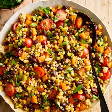 a bowl with pearl couscous, black beans, corn, bell peppers, cherry tomatoes, scallions, cilantro, and pickled jalapenos