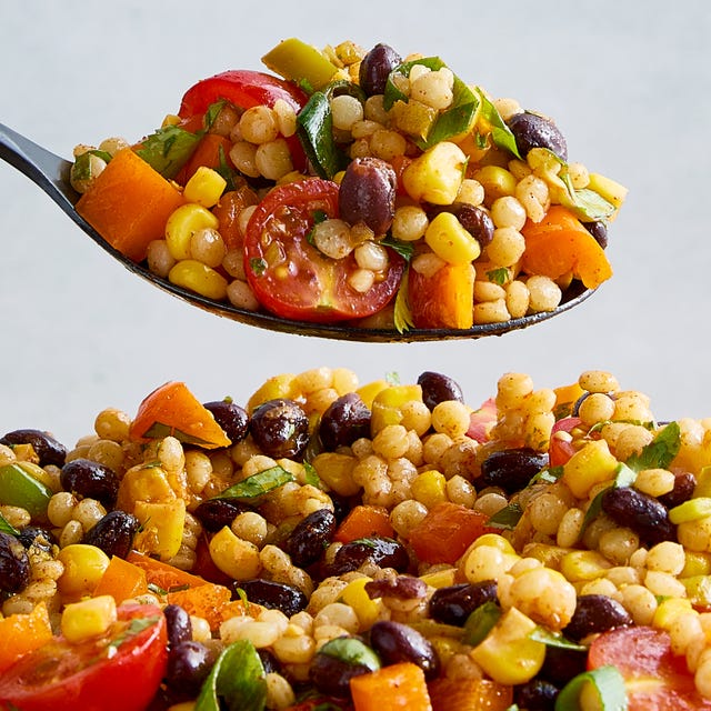 a bowl with pearl couscous, black beans, corn, bell peppers, cherry tomatoes, scallions, cilantro, and pickled jalapenos