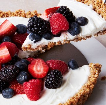 a slice of no bake fruit and granola breakfast tart topped with blueberries, blackberries, raspberries, and strawberries lifting out of the larger tart