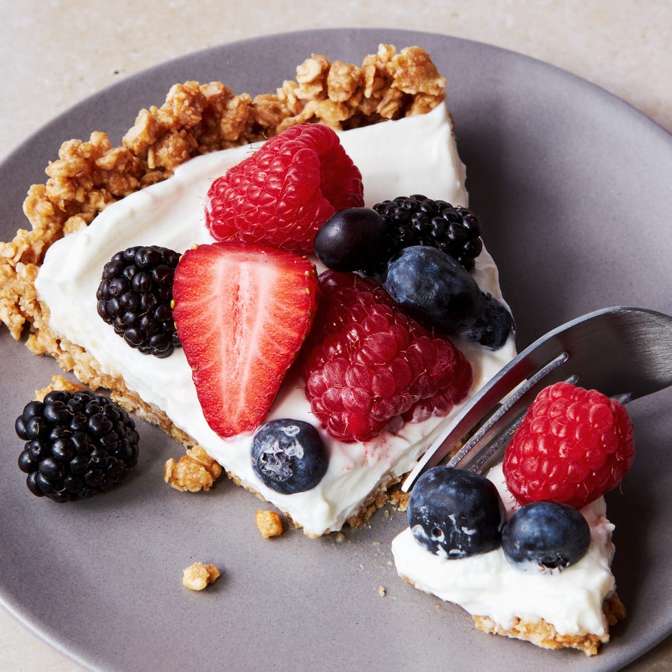 a slice of no bake fruit and granola breakfast tart topped with blueberries, blackberries, raspberries, and strawberries on a plate