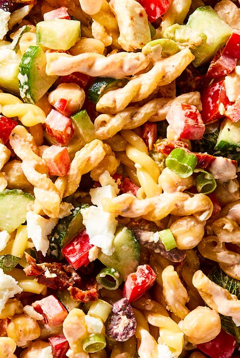 gemelli pasta tossed with chickpeas, bell pepper, cucumber, scallions, feta, olives, herbs, and tomatoes, then tossed in harissa mayo