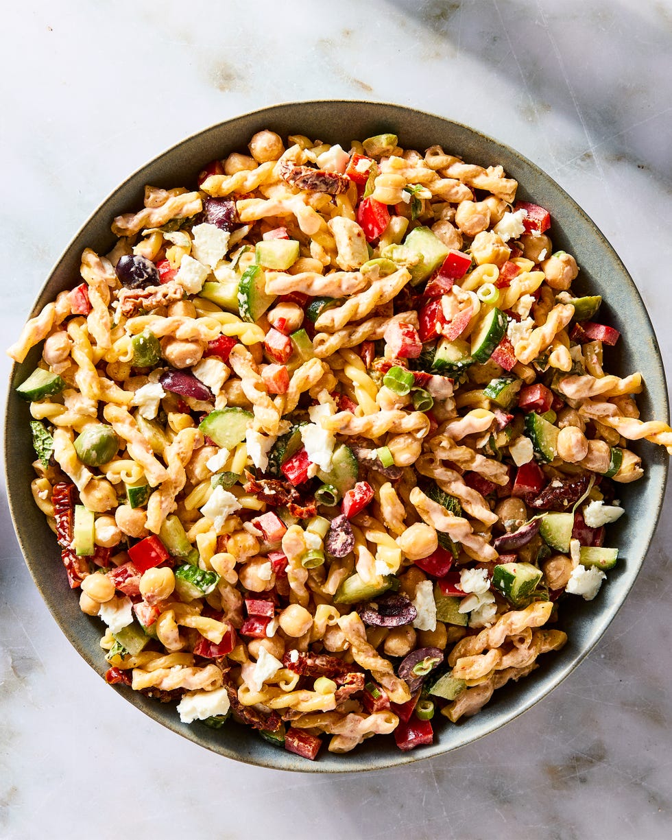 gemelli pasta tossed with chickpeas, bell pepper, cucumber, scallions, feta, olives, herbs, and tomatoes, then tossed in harissa mayo