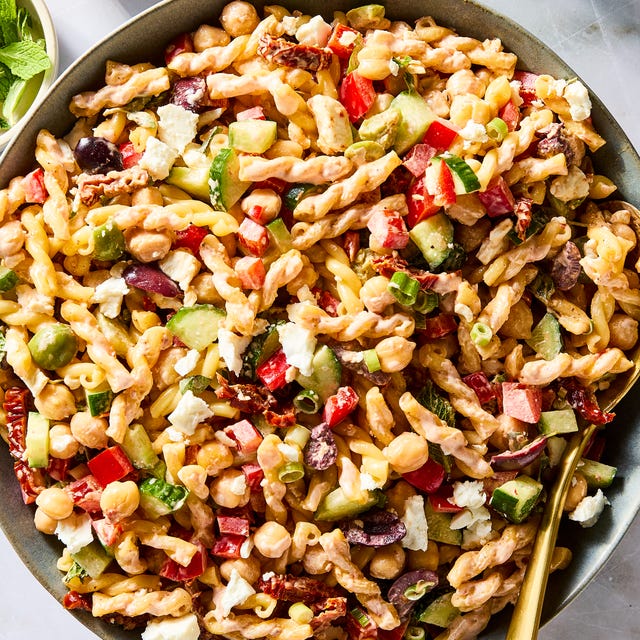 gemelli pasta tossed with chickpeas, bell pepper, cucumber, scallions, feta, olives, herbs, and tomatoes, then tossed in harissa mayo