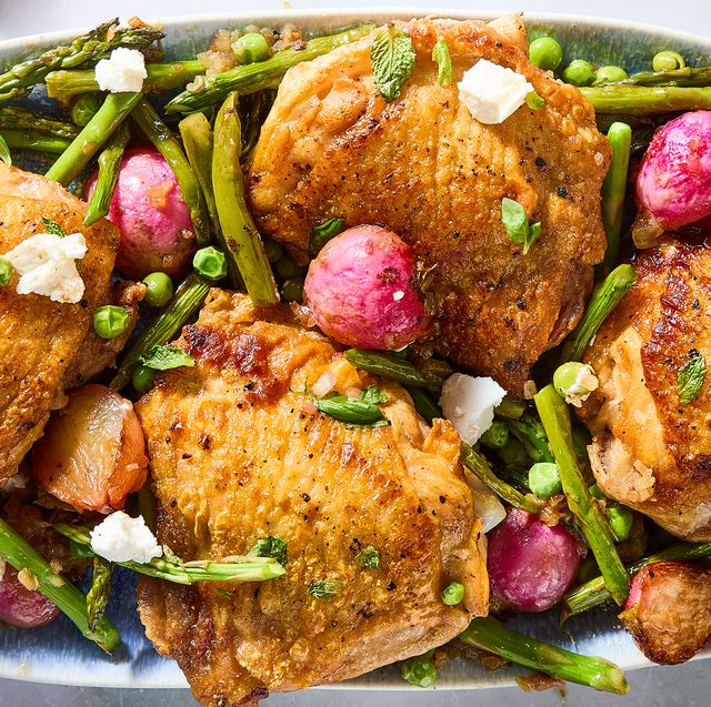 crispy chicken thighs with roasted radishes, asparagus, and peas on a white platter