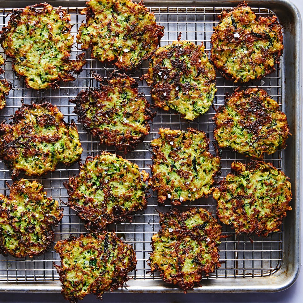 a tray of fried zucchini fritters with a bowl of marinara sauce