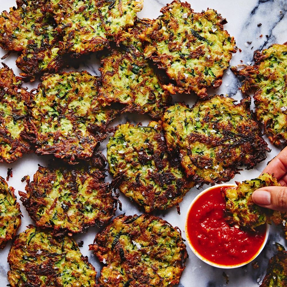 a tray of fried zucchini fritters with a bowl of marinara sauce