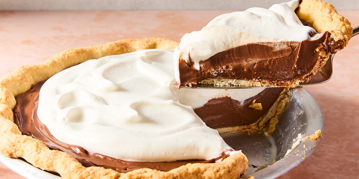 a slice of chocolate cream pie lifting out of the larger pie