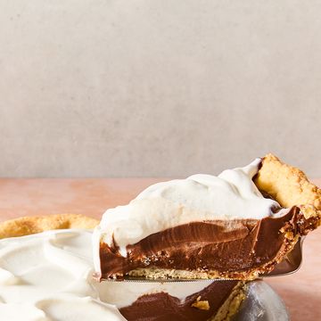 a slice of chocolate cream pie lifting out of the larger pie