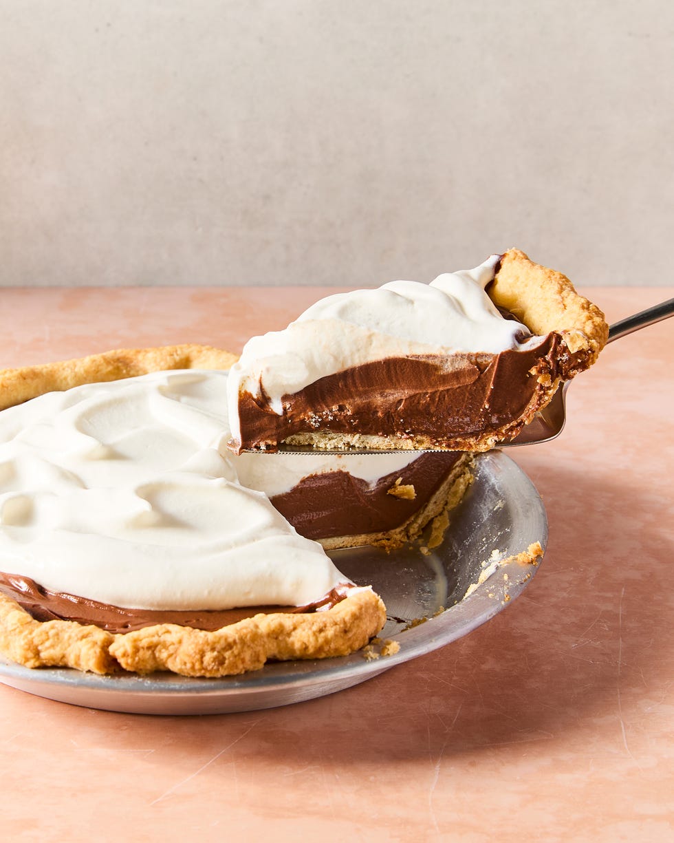 a slice of chocolate cream pie lifting out of the larger pie