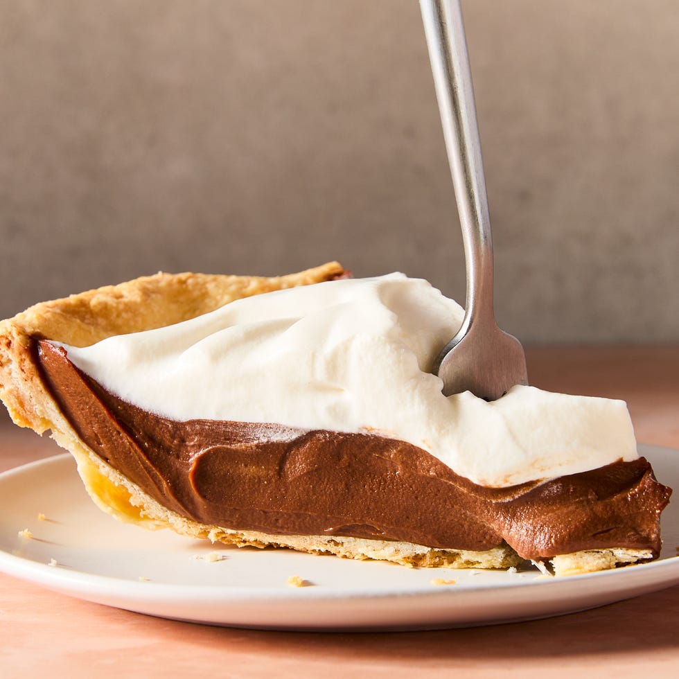 a slice of chocolate cream pie on a plate with a fork stabbed into it
