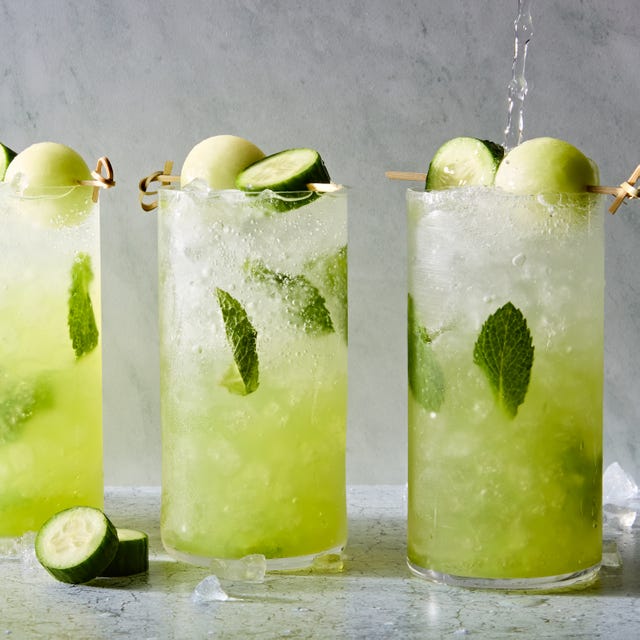 Cucumber Melon Mojito a glass filled with ice, rum, mint leaves, midori liqueur, and lime juice garnished with a cucumber slice and honeydew melon ball
