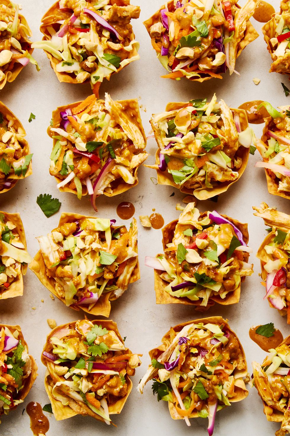 shredded rotisserie chicken gets tossed in a spicy sweet peanut sauce, stuffed in a crispy baked wonton shell, and topped with bright, colorful, and crunchy veggies to make this easy two bite app
