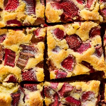 a tray of square slices of cake with strawberry and rhubarb pieces distributed throughout