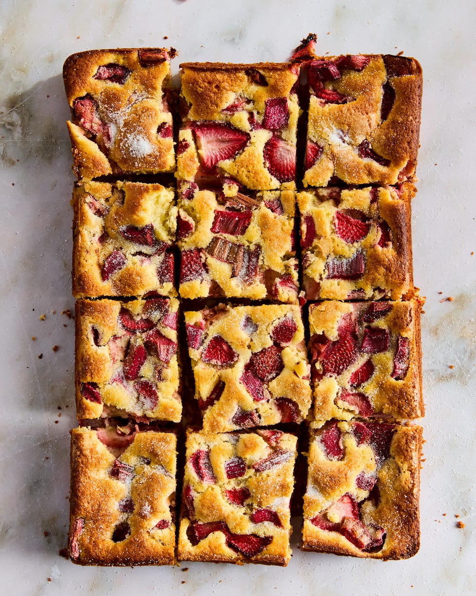 a tray of square slices of cake with strawberry and rhubarb pieces distributed throughout