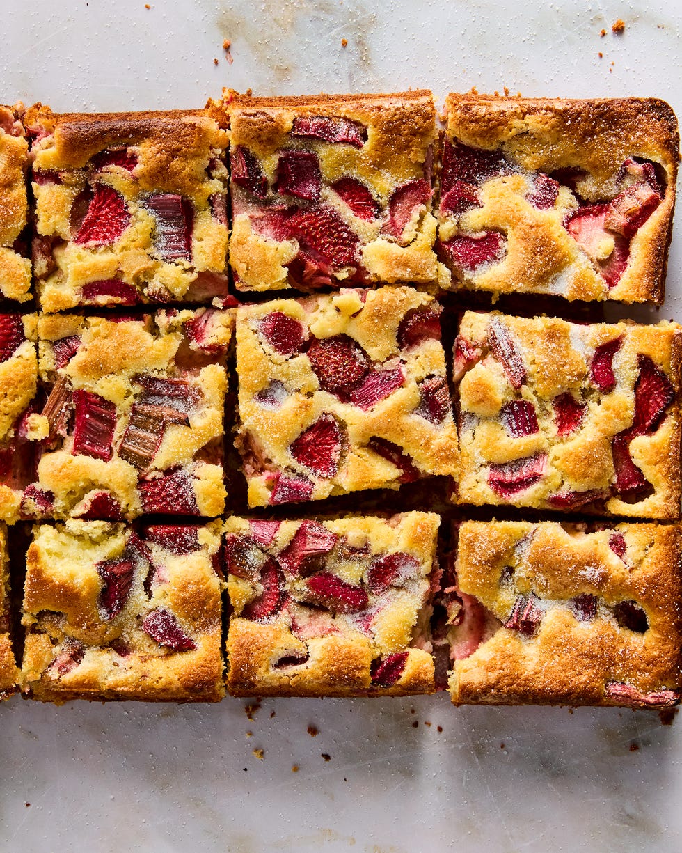 a tray of square slices of cake with strawberry and rhubarb pieces distributed throughout