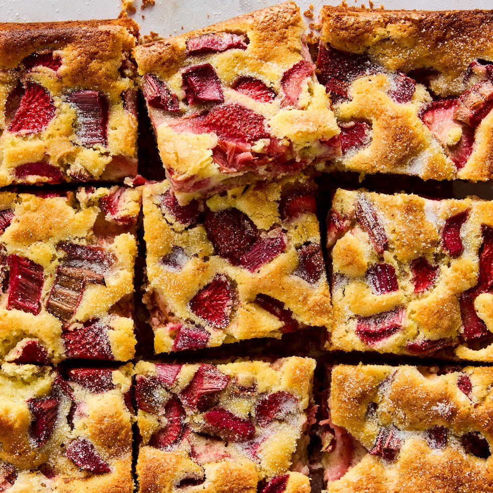 a tray of square slices of cake with strawberry and rhubarb pieces distributed throughout