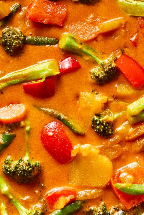 a pot of thai style curry in a coconut milk broth with broccoli, potatoes, carrots, and peppers