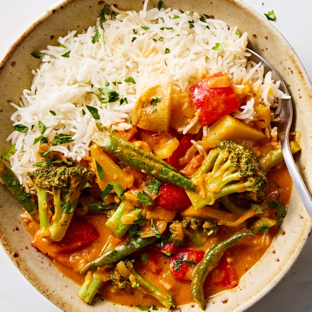 a pot of thai style curry in a coconut milk broth with broccoli, potatoes, carrots, and peppers