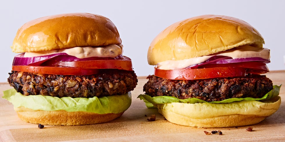 veggie burgers topped with lettuce, tomato, red onion, and chipotle mayo on a wood board