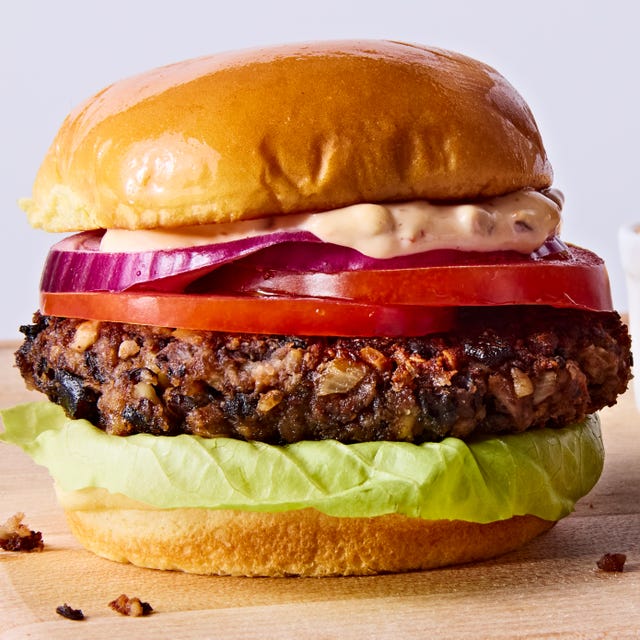 veggie burger topped with lettuce, tomato, red onion, and chipotle mayo on a wood board