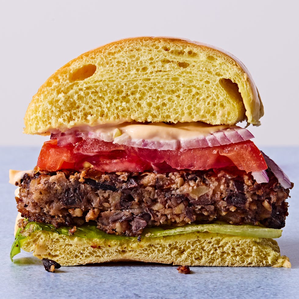 a cross section of a veggie burger topped with tomato, red onion, and chipotle mayo