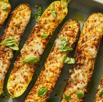 cheesy garlic zucchini steaks on a greek plate topped with basil and red pepper flakes