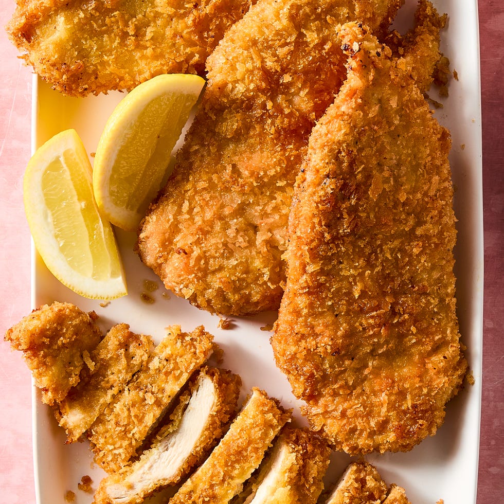 Chicken cutlets chicken cutlets on a white serving platter with lemon wedges