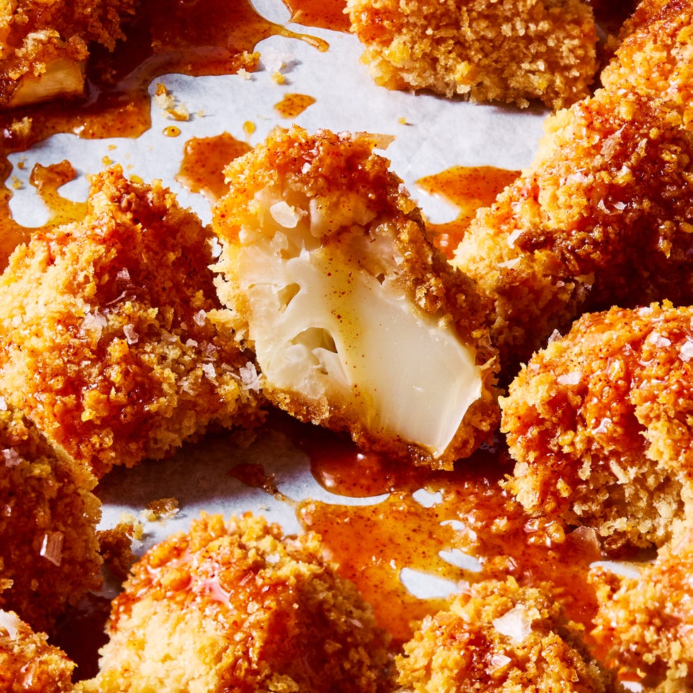 crispy hot honey cauliflower nugget cut open, surrounded by drizzles of hot honey sauce